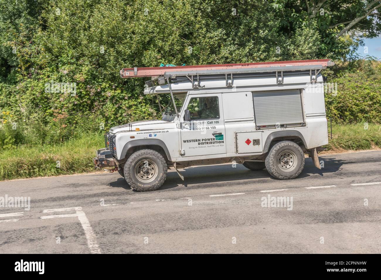 White Land Rover est utilisé comme véhicule utilitaire pour Western Power distribution sur une route rurale de Cornwall. WPD est le principal fournisseur d'électricité de Cornish Banque D'Images