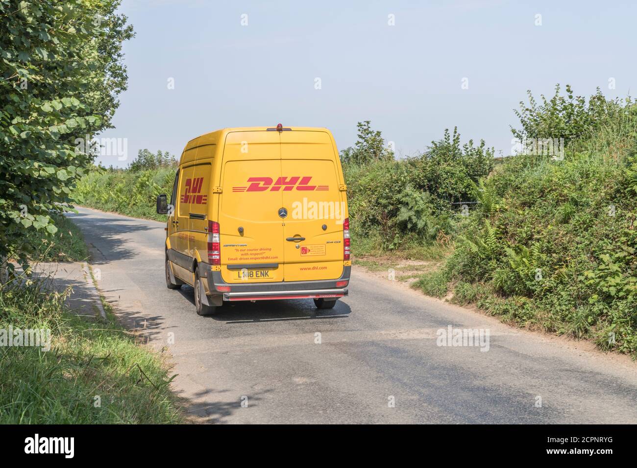 Minibus de livraison jaune DHL (Mercedes Sprinter) sur une route rurale Cornish. Pour les services de livraison rurale au Royaume-Uni, les livraisons de colis, les services de messagerie. Banque D'Images