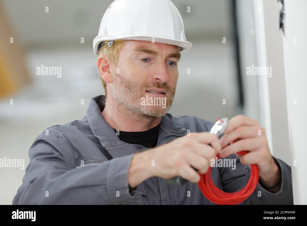 électricien coupant le fil rouge avec des coupe-câbles Banque D'Images