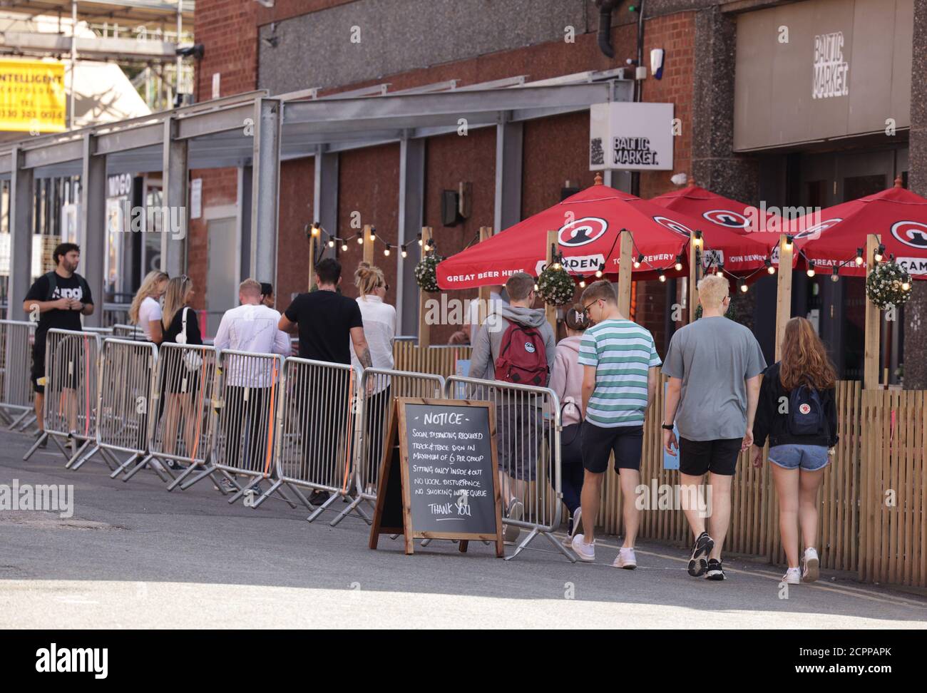 Des gens qui font la queue socialement pour entrer sur le marché Baltique à Liverpool. Banque D'Images