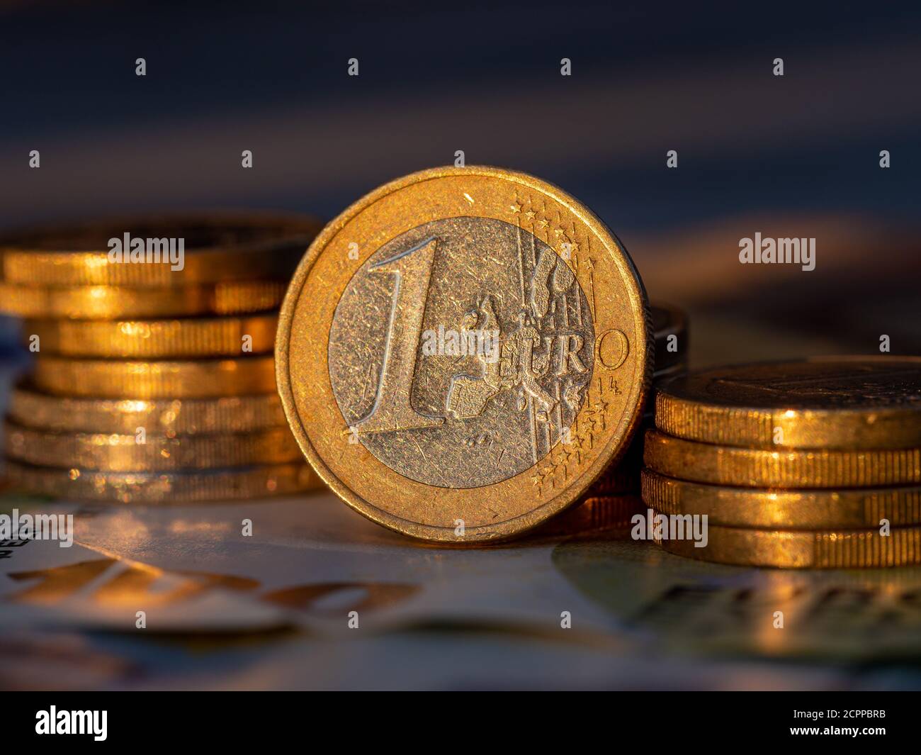 Vue rapprochée d'une pièce d'un euro avec piles de pièces d'un centiret d'euro. Banque D'Images