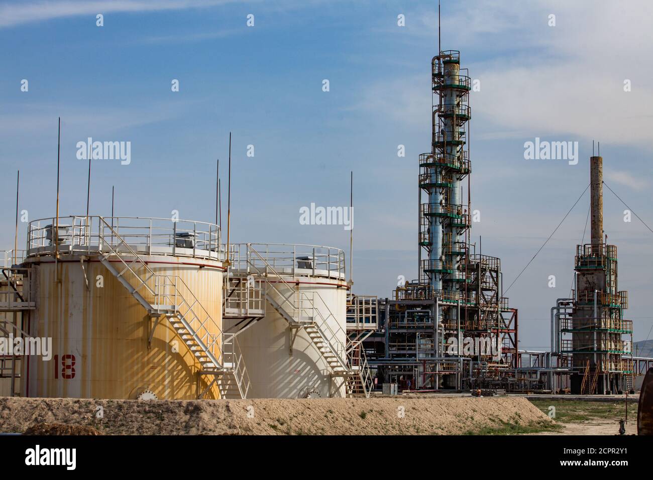 Réservoirs d'huile blancs et jaunes et colonne de distillation fractionnelle au ciel bleu. Raffinerie de pétrole dans le désert. Près de la ville de Taraz. Banque D'Images