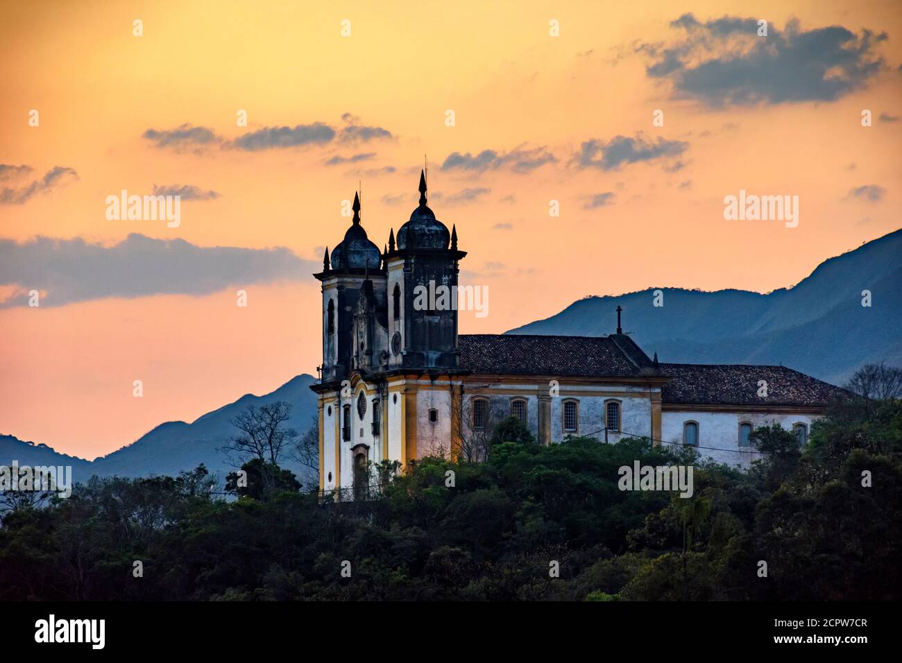 Ancienne église historique au sommet de la colline au coucher du soleil dans la ville d'Ouro Preto à Minas Gerais, Brésil avec les montagnes derrière Banque D'Images