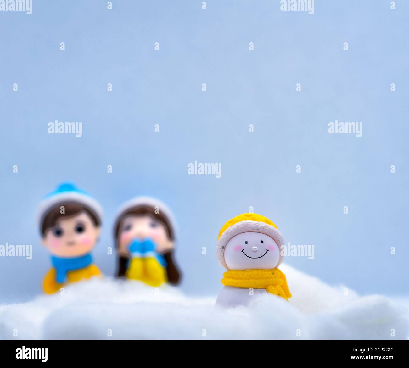 Tourisme et Voyage concept: Petit bonhomme de neige miniature dans la neige d'hiver avec couple en arrière-plan Banque D'Images