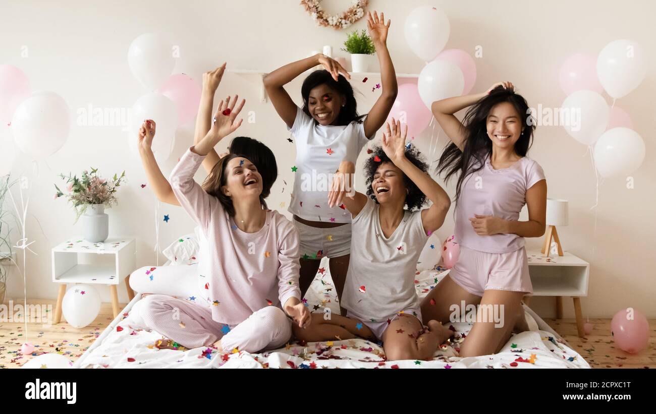 Jeunes dynamiques diverses filles multiethniques jouant avec des confettis colorés. Banque D'Images