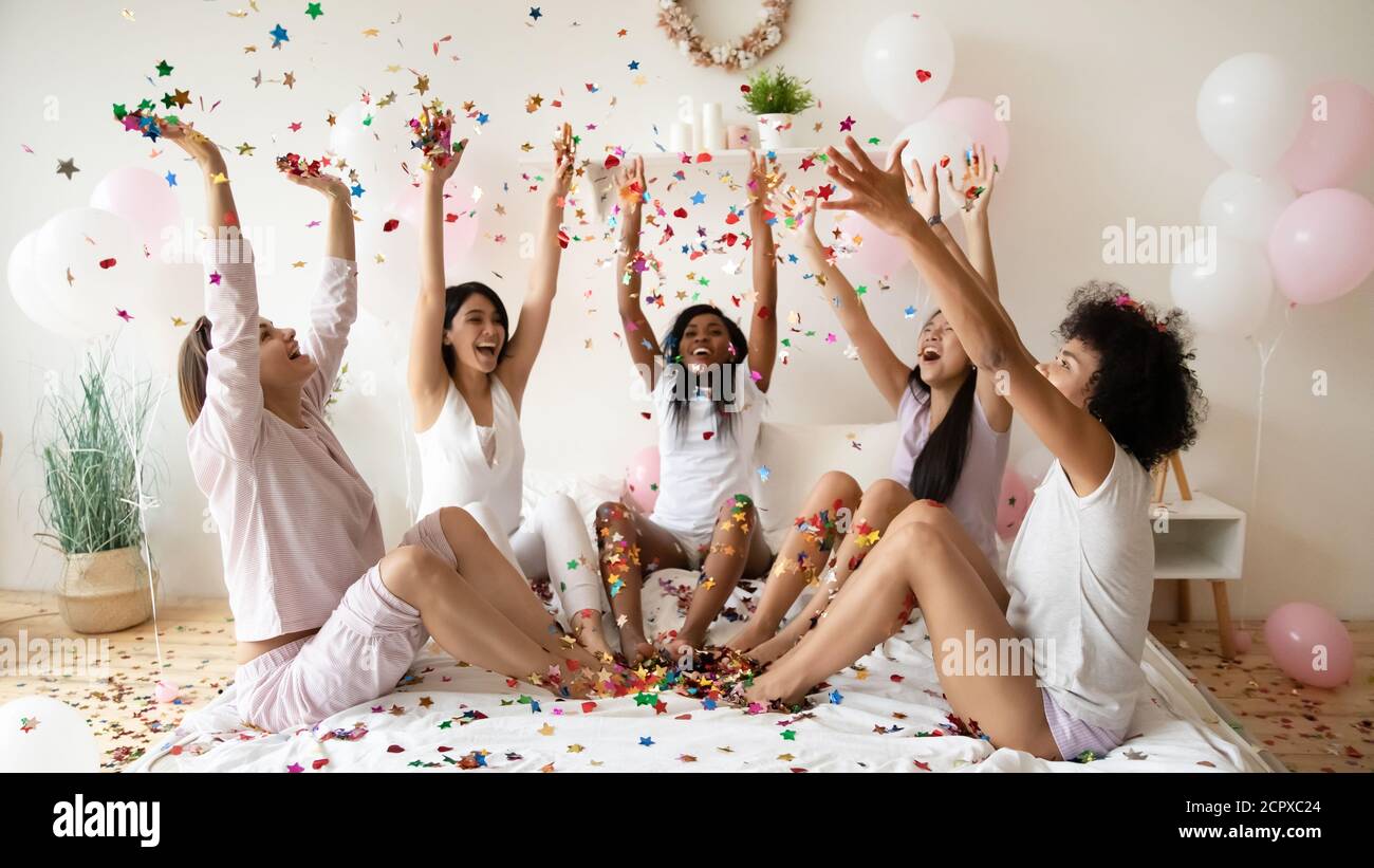 Jeunes festifs divers femmes meilleurs amis jeter des confettis dans l'air. Banque D'Images