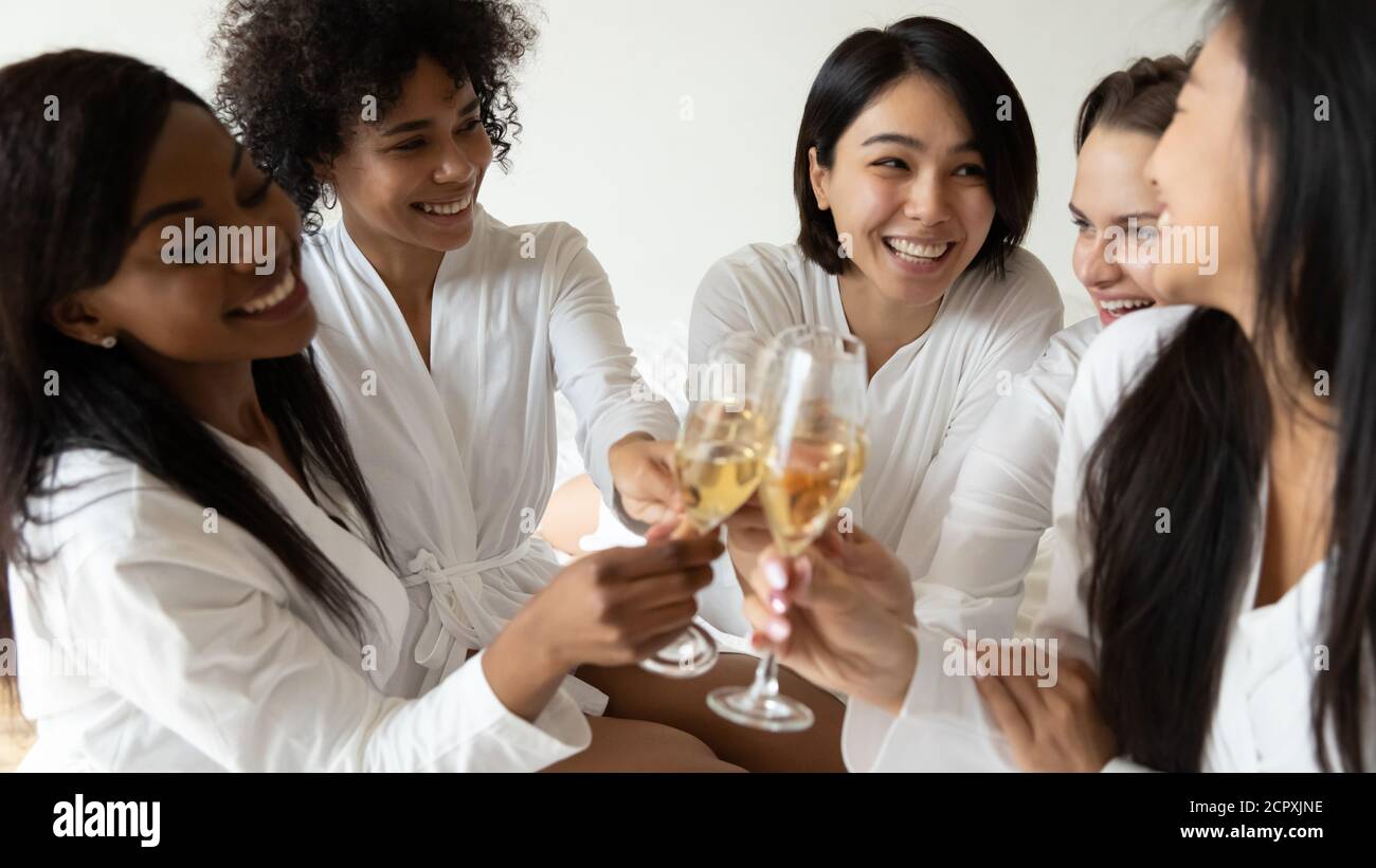 Joyeux jeune multiracial meilleurs amis célébrant l'anniversaire spa avec du vin. Banque D'Images