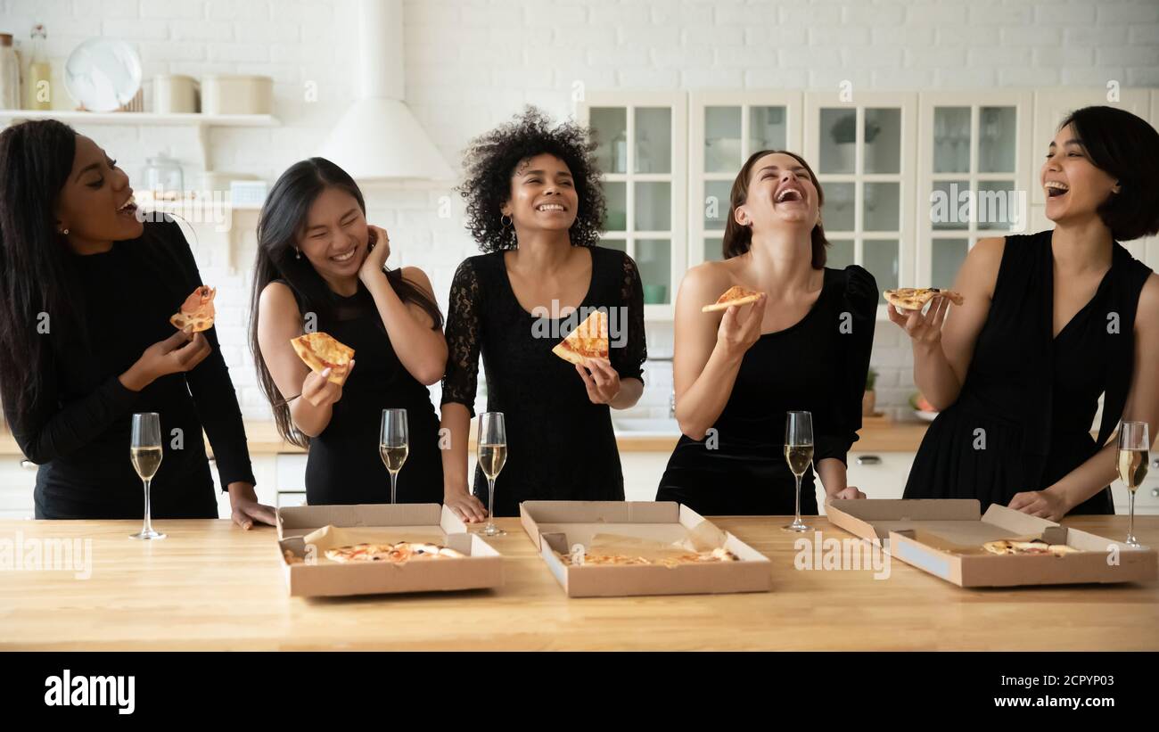 Surjoyée jeune attrayante multiraciale femme besties manger de la pizza de boîte. Banque D'Images