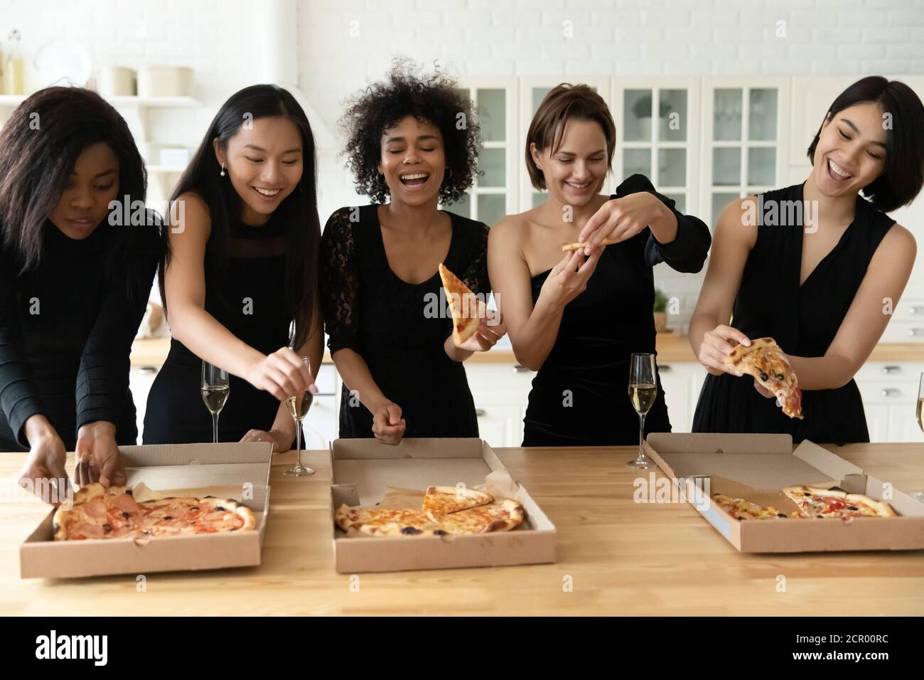 Joyeux jeune festive mixte race belles femmes manger de la pizza. Banque D'Images