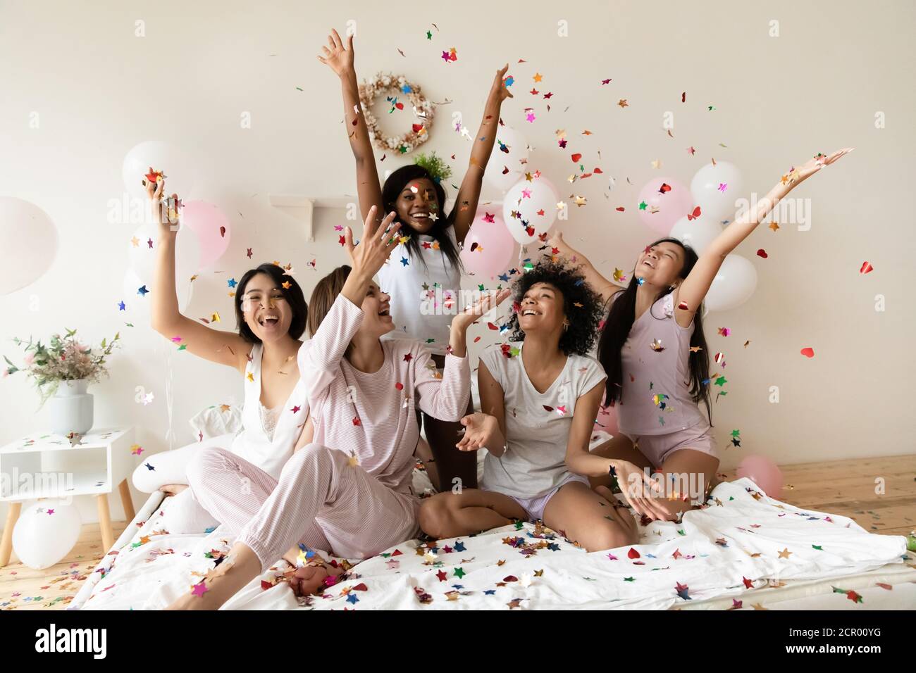 Joyeux jeune festive mixte race diverses femmes jouant avec des paillettes. Banque D'Images