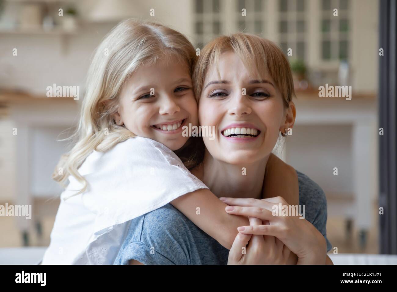 Une mère joyeuse se câliner avec son enfant à la maison et souriant Banque D'Images