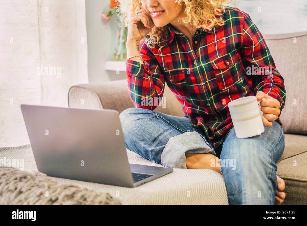 Femme heureuse et gratuite à la maison avec ordinateur portable et tasse de thé - technologie et concept de personnes adultes - communication et activité de connexion - intelligent Banque D'Images