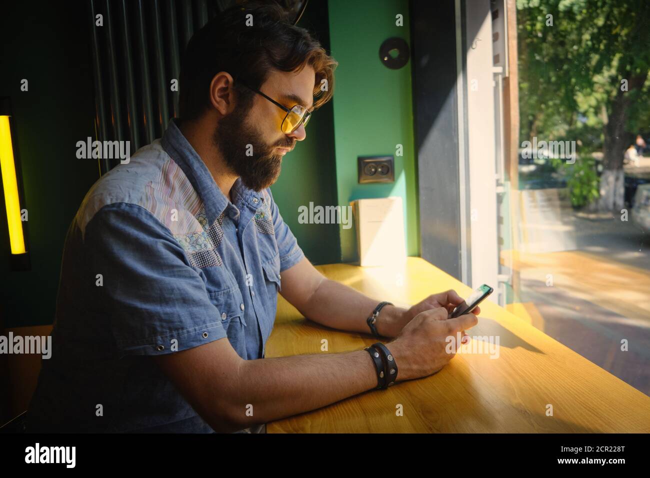 Homme tient le téléphone et chat en ligne assis dans un café Banque D'Images