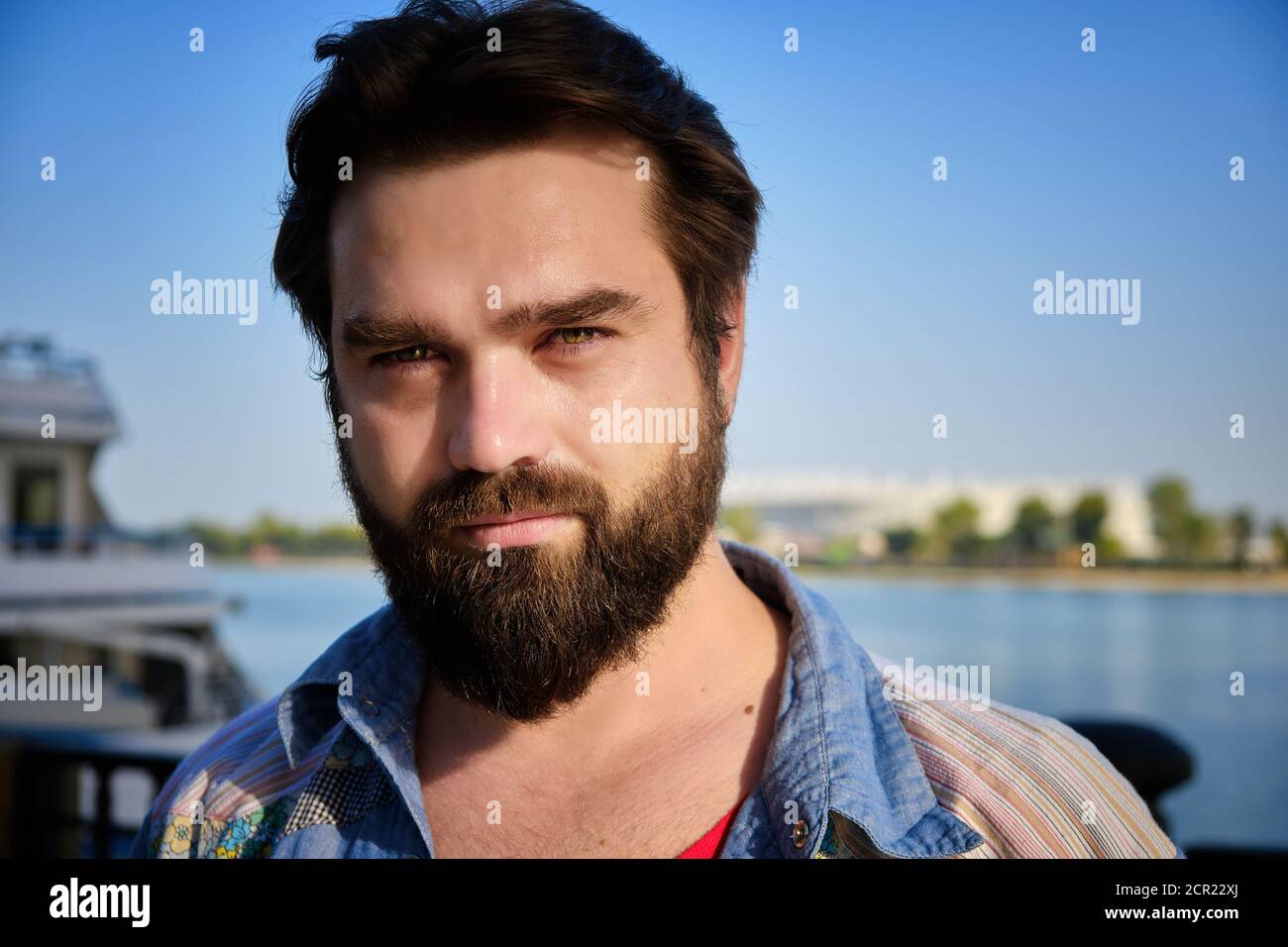 Portrait d'un homme caucasien barbu avec une rivière et un ciel bleu en arrière-plan Banque D'Images