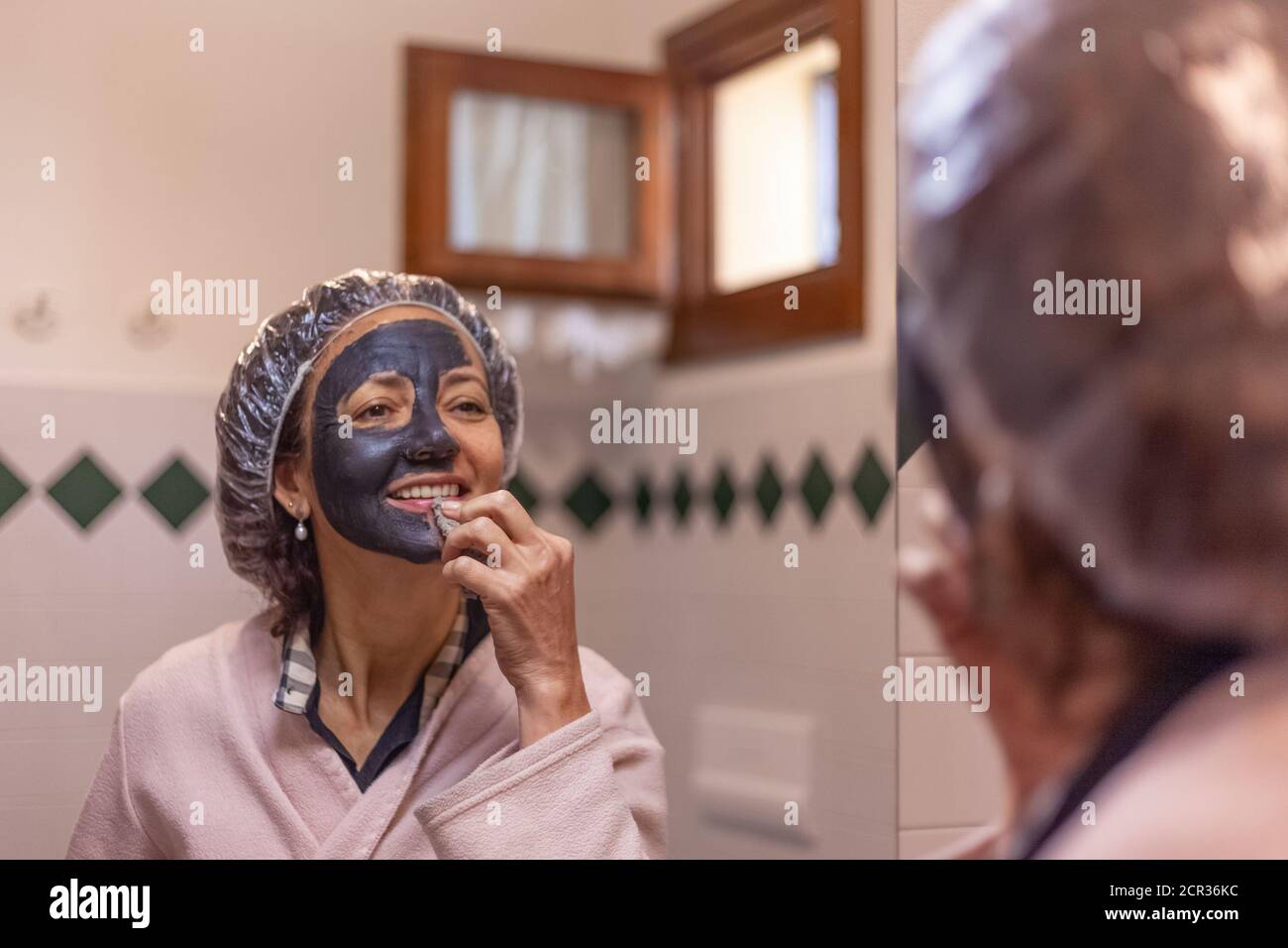 Gros plan d'une femme réfléchie sur un miroir lors de la suppression le masque de boue Banque D'Images
