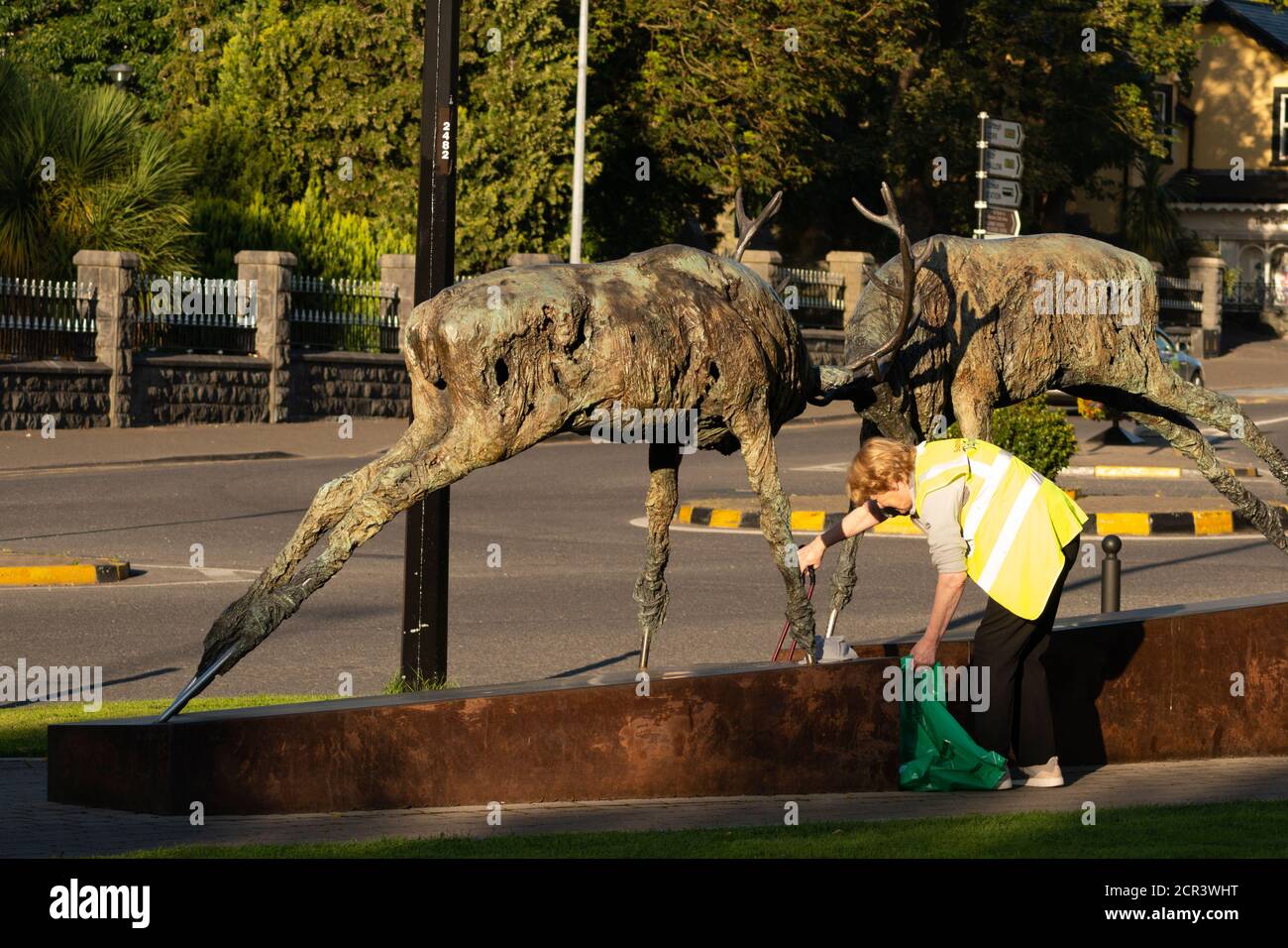 Femme volontaire de nettoyage des villes de Killarney en Irlande la portée à la statue populaire de ville comme le bénévolat est un populaire activité parmi les locaux Banque D'Images