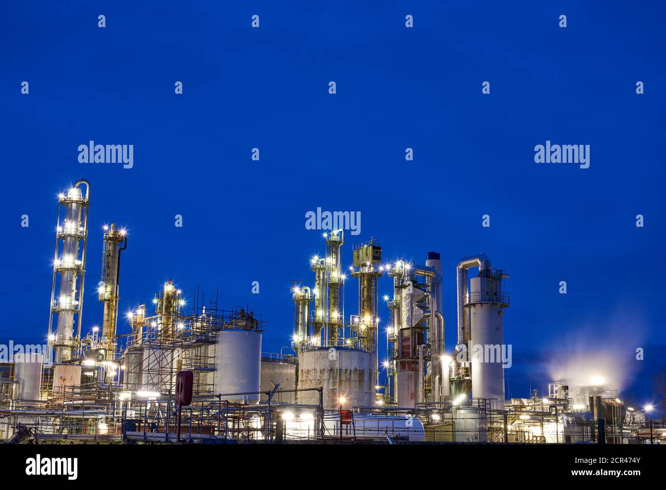Raffinerie de pétrole avec tour de refroidissement avec refroidissement libre après coucher de soleil avec lumières Banque D'Images