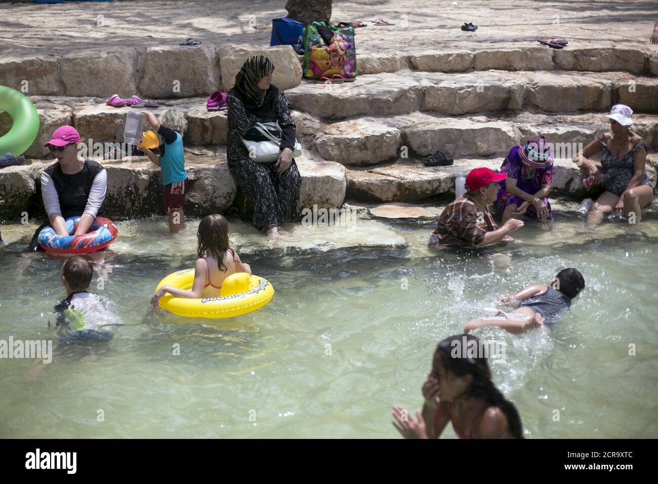 Une femme musulmane (C) se trouve à côté d'une piscine dans le parc national de Gan Hashlosha, également connu sous son nom arabe Sahne, près de la ville de Beit Shean dans la vallée du Jourdain le 5 août 2015. Israël a fait des sweltering ces derniers jours sous des températures extrêmement chaudes et une humidité oppressive, enregistrant une consommation record d'électricité pour alimenter les climatiseurs. REUTERS/Baz Ratner Banque D'Images