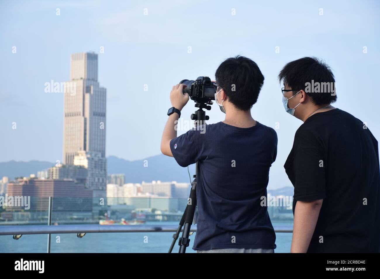 Deux hommes asiatiques vus du dos qui prennent des photos Des bâtiments et de la ligne d'horizon de l'île de Hong Kong Banque D'Images