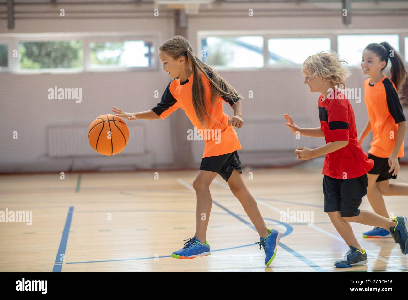 Enfants dans des vêtements de sport brillants jouant au basket-ball  ensemble et se sentant sous tension Photo Stock - Alamy