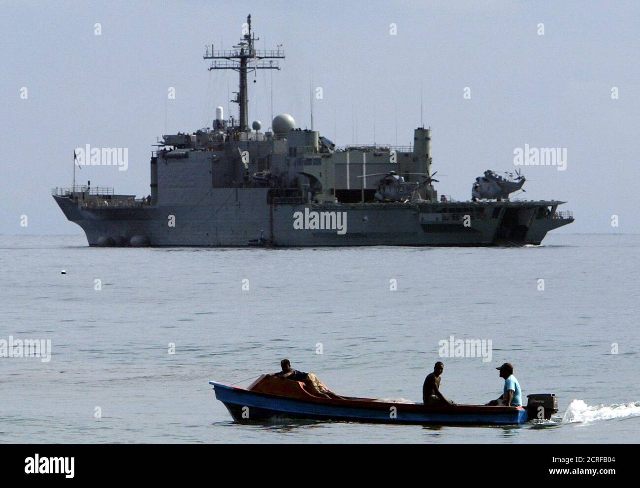 Un bateau de pêche passe devant le navire de la marine australienne HMAS  Manoura après son arrivée à Red Beach, situé juste à l'extérieur de la  capitale de l'île Salomon, Honiara, le