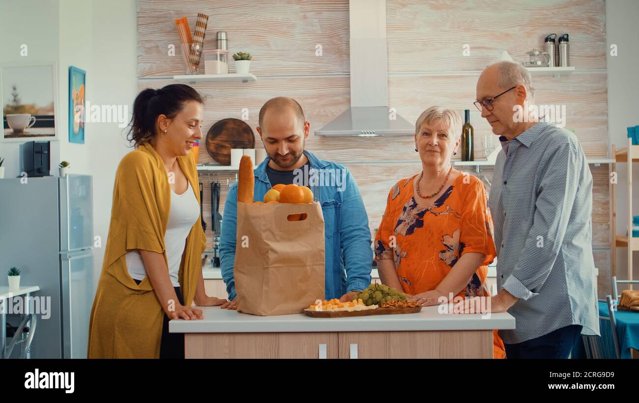 Portrait vidéo de la famille étendue heureuse souriant à l'appareil photo, assis dans la cuisine. Les gens dans la salle à manger autour du sac de papier avec des provisions regardant la web CAM Banque D'Images
