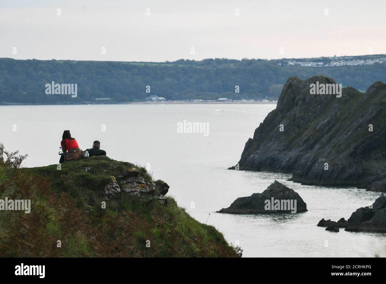 Swansea, pays de Galles, 15 septembre 2020. Météo au Royaume-Uni : deux personnes regardent la marée haute la faire rouler à trois falaises Bay sur la côte de Gower, Swansea au premier feu le dimanche matin à marée haute. Les prévisions sont pour une autre belle journée au Royaume-Uni comme le sort du bon temps continue. Crédit : Robert Melen/Alamy Live News Banque D'Images