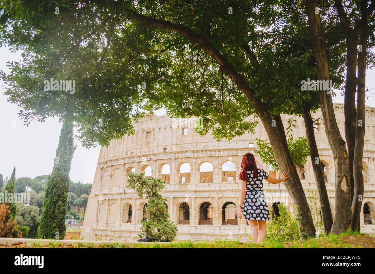 Rome, Italie - UNE jeune femme brésilienne adulte à tête rouge dans ses années 20s debout et regardant dans le Colisée pris dans un parc pendant l'après-midi. Banque D'Images