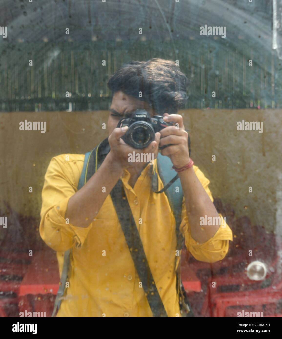 Un garçon indien clique sur l'image de lui-même à travers le miroir avec l'appareil photo nikon. Banque D'Images