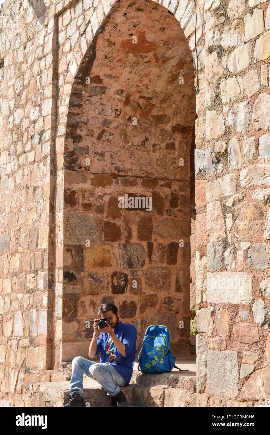 Un garçon indien qui se pose et clique sur une photo de l'ancien fort qui donne la pose pour une séance photo de mode. Banque D'Images
