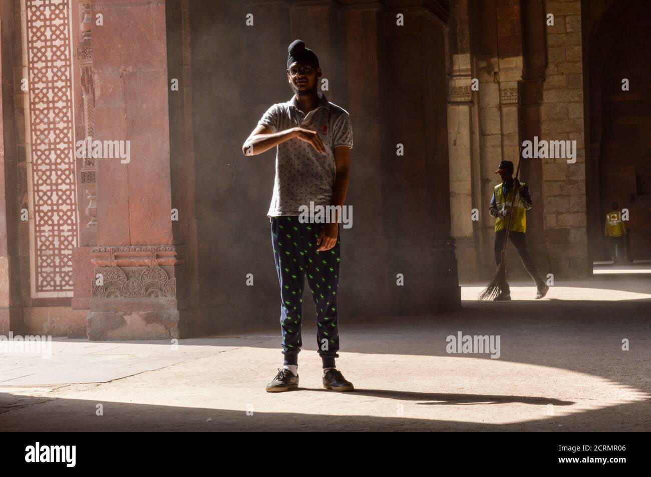 Un garçon indien qui pose pour une séance photo de mode à l'intérieur du vieux fort et un employé de l'ASI qui nettoie la zone. Banque D'Images