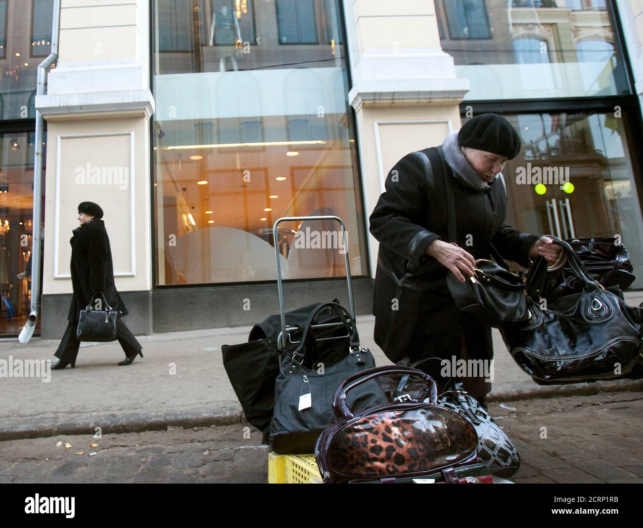 Une femme vend des sacs à main devant les boutiques de vêtements Alexander  McQueen et Stella McCartney à Moscou le 27 mars 2009. Les femmes  Kercheffées ont pédalier des faux sacs à