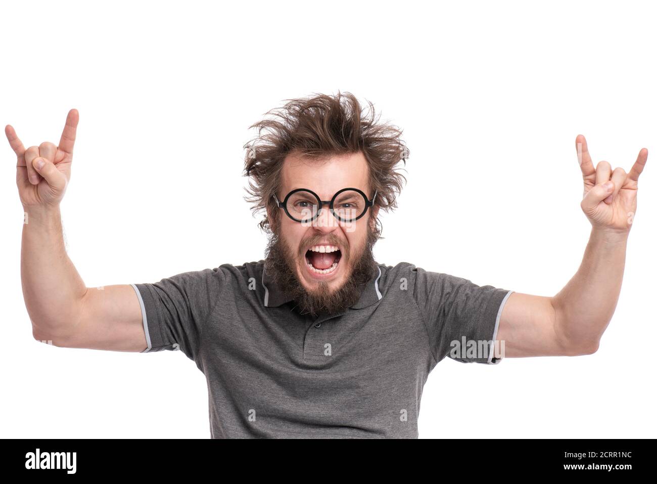 Fou Bearded Happy Man avec une coupe de cheveux drôle en lunettes de vue faisant le mouvement de rock et de rouleau. Un gars gai et stupide, isolé sur fond blanc. Banque D'Images