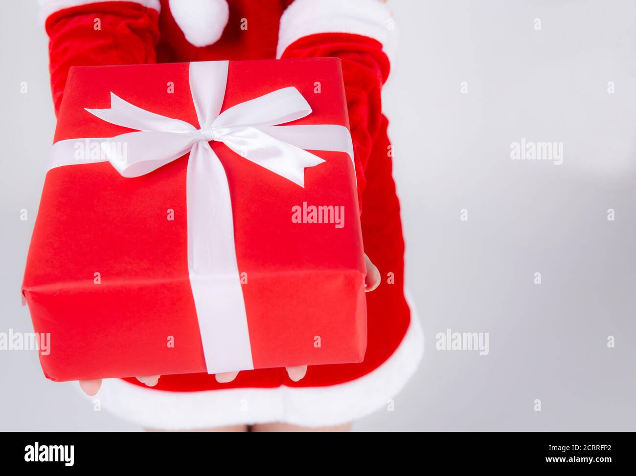 Gros plan main femme tenant la boîte cadeau dans le jour de Noël avec surprise isolé sur fond blanc, bras fille heureux donner rouge boîte cadeau avec papier d'emballage et wh Banque D'Images