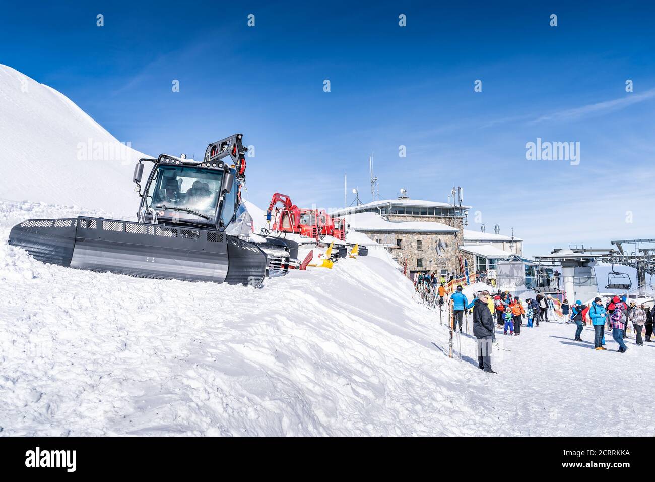 Zakopane, Pologne Mars 2019 touristes visitant le sommet de Kasprowy Wierch avec de multiples tondeuses à neige garées sur place et des remontées mécaniques en arrière-plan Banque D'Images