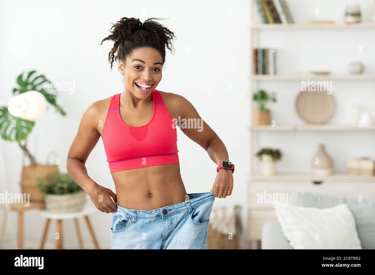 Femme excitée portant trop de grands jeans après perte de poids intérieur Banque D'Images