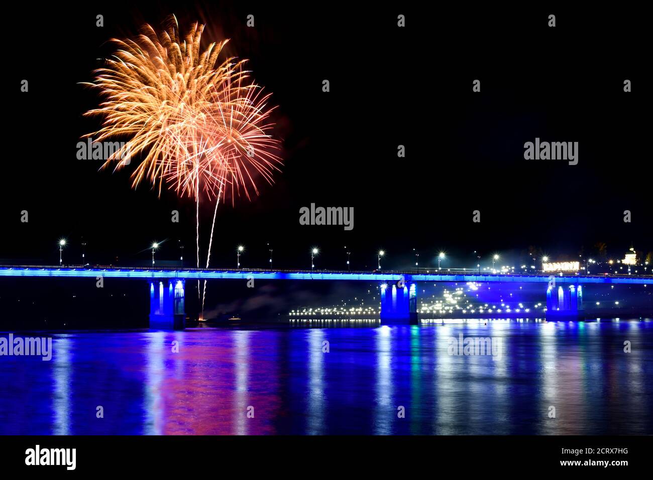 Feux d'artifice festifs colorés, saluez le pont avec un éclairage bleu, des remblais et des reflets dans l'eau de la rivière Banque D'Images