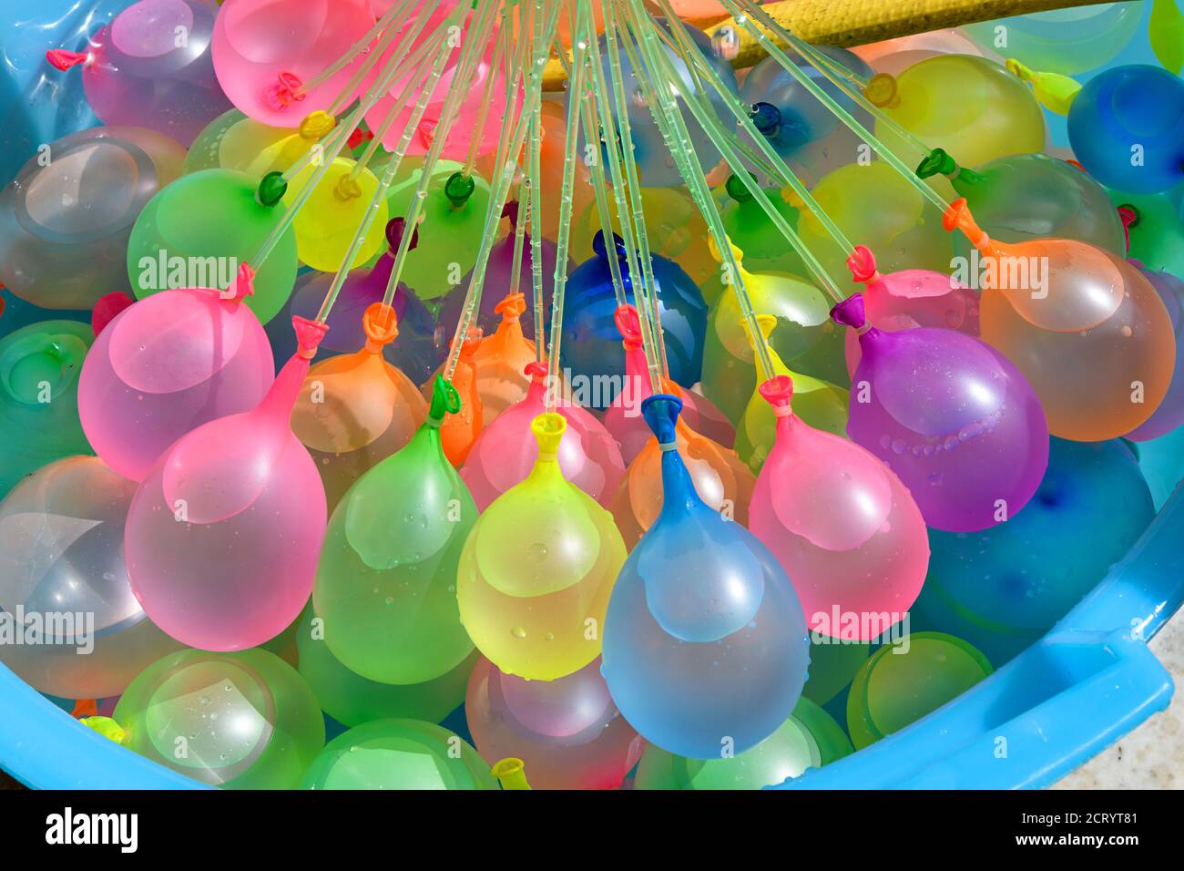 Remplir d'eau une baignoire remplie de ballons en caoutchouc colorés pour une utilisation comme bombes à eau pour refroidir en été lors d'une fête ou d'un carnaval Banque D'Images