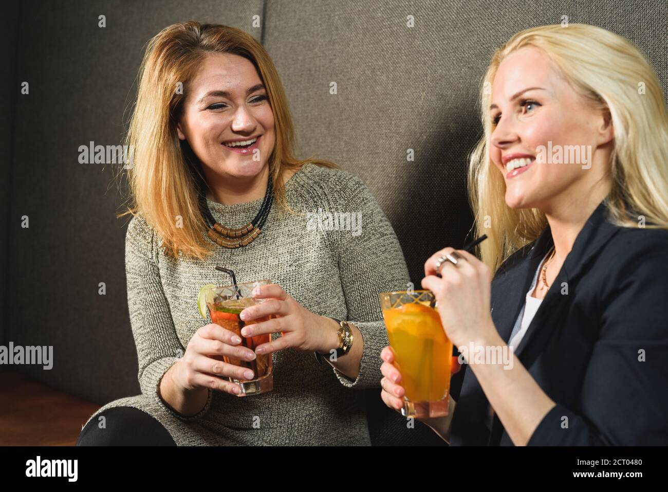Des amies ravie de boire des cocktails et de rire à la plaisanterie le week-end journée au bar Banque D'Images