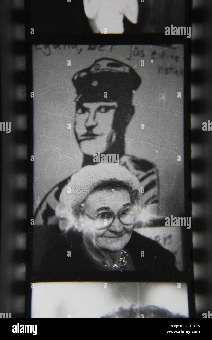 Belle photographie en noir et blanc vintage des années 1970 d'une femme debout devant un dessin d'un homme portant un uniforme communiste. Banque D'Images