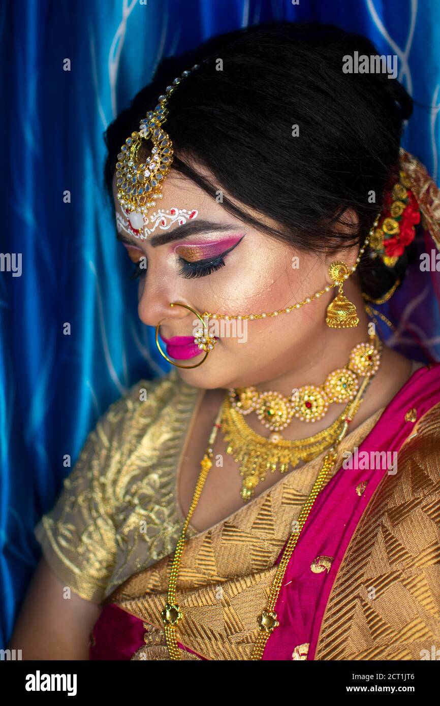 Portrait d'un adorable modèle indien à l'aspect de la mariée avec bijoux en or épais et sari rouge Banque D'Images