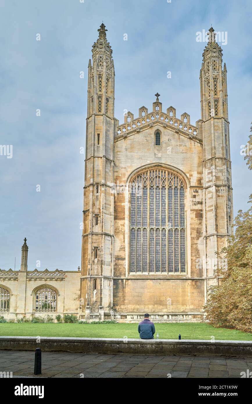 Un homme solitaire est assis sur le mur inférieur à l'extérieur de la fenêtre est de la chapelle du King's College, université de Cambridge, Angleterre, pendant la crise du coronavirus. Banque D'Images