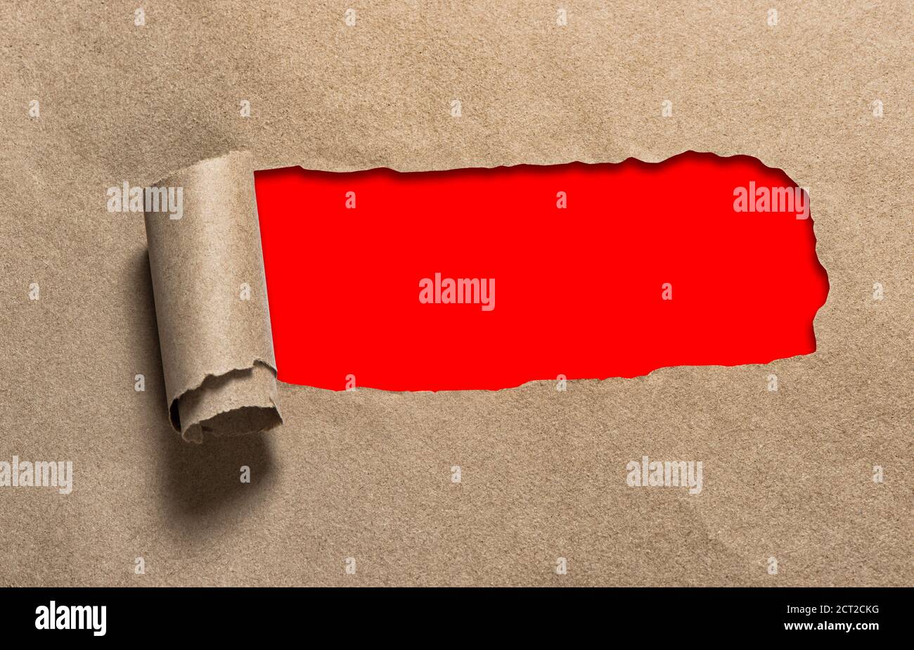 Trou déchiré dans le papier artisanal avec espace de copie rouge Banque D'Images