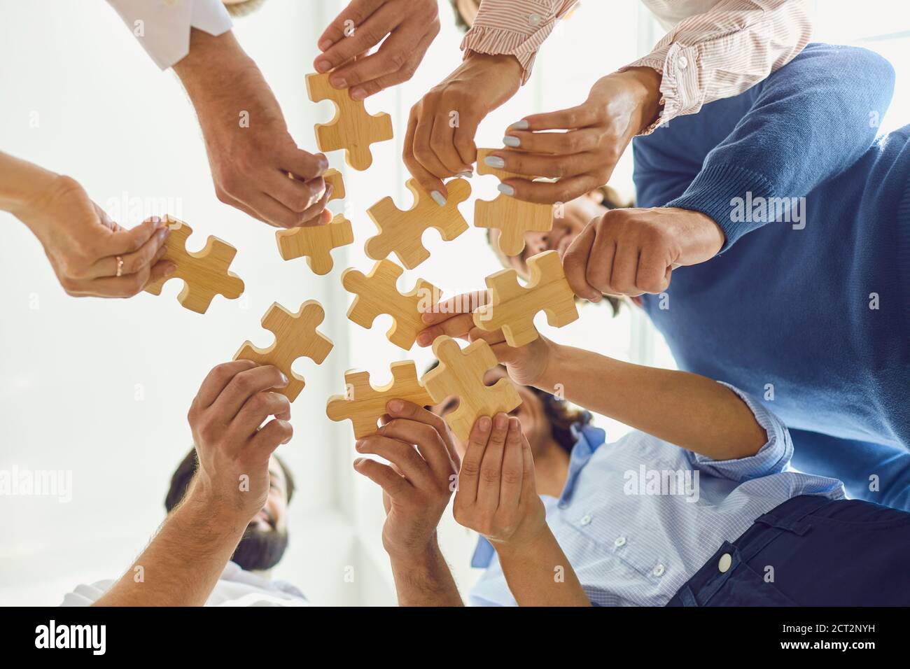 Des employés d'entreprise positifs jouant avec un puzzle pendant la construction d'une équipe activité Banque D'Images