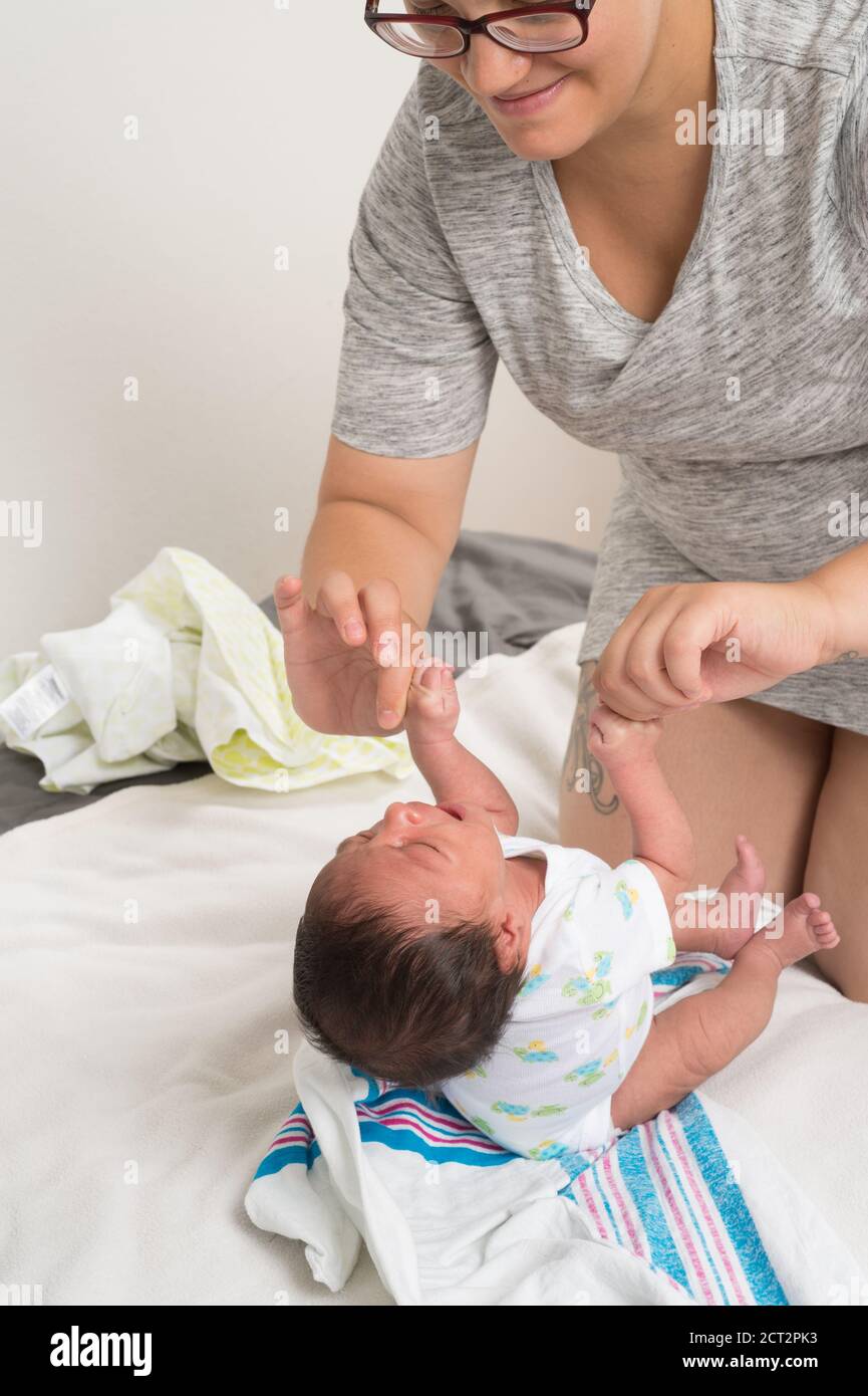 Réflexe de nouveau-né de garçon : saisissez les pouces de la mère à la verticale Banque D'Images