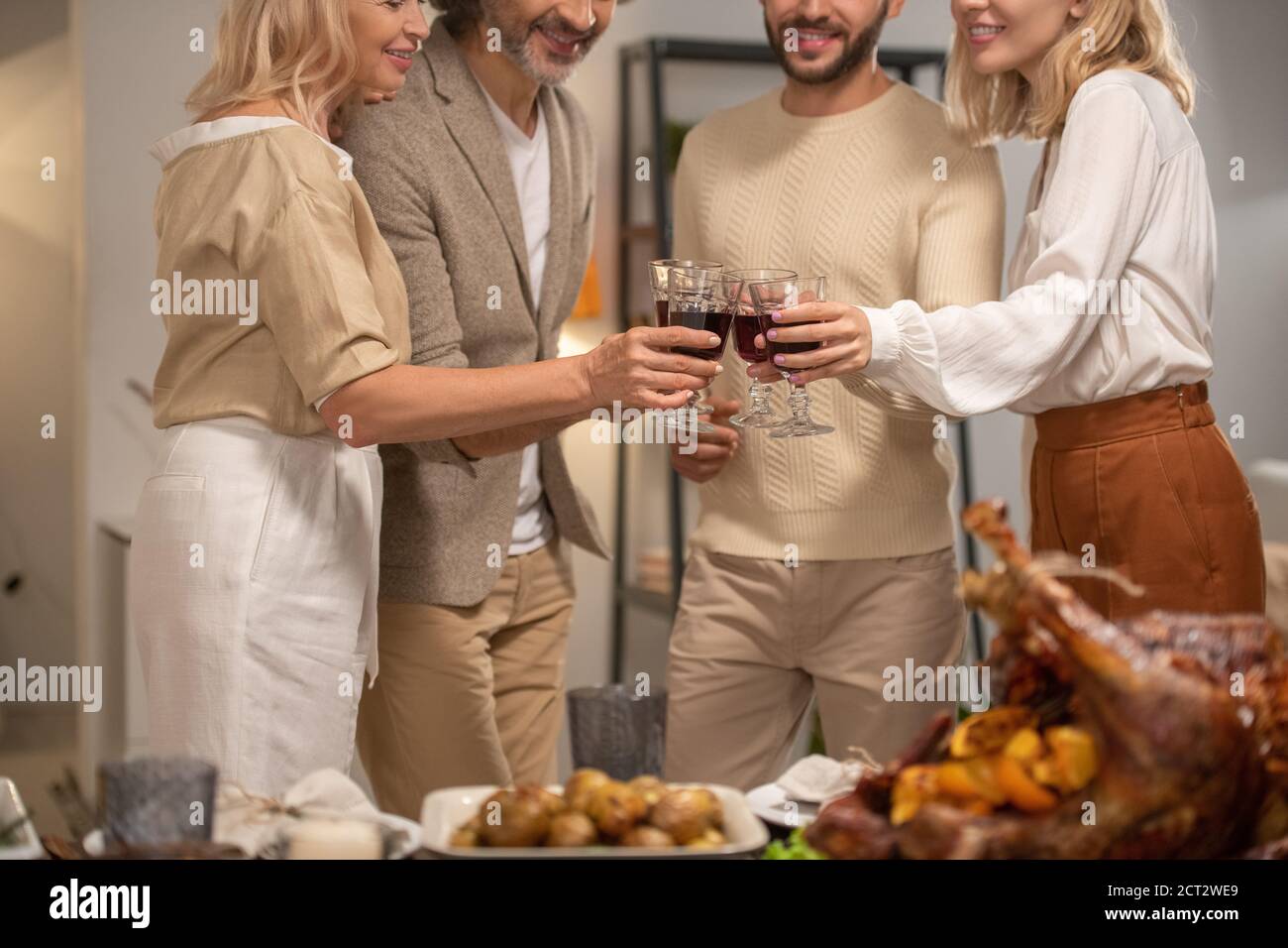Les mains de quatre membres de la famille souriants en tenue décontractée se clinquant avec verres de vin Banque D'Images