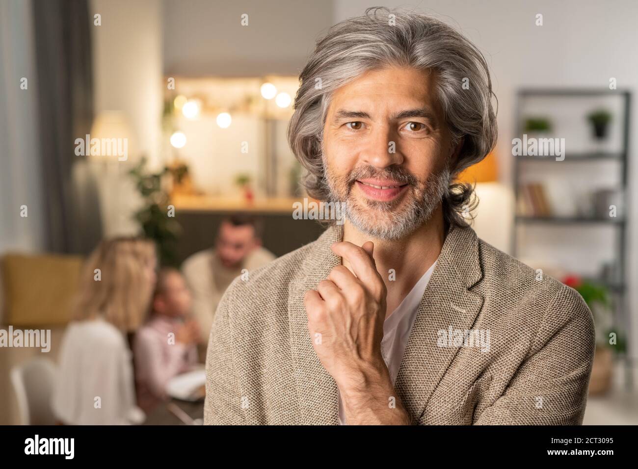 Joyeux homme mature barbu en tenue décontractée touchant le menton tout en regardant à vous Banque D'Images