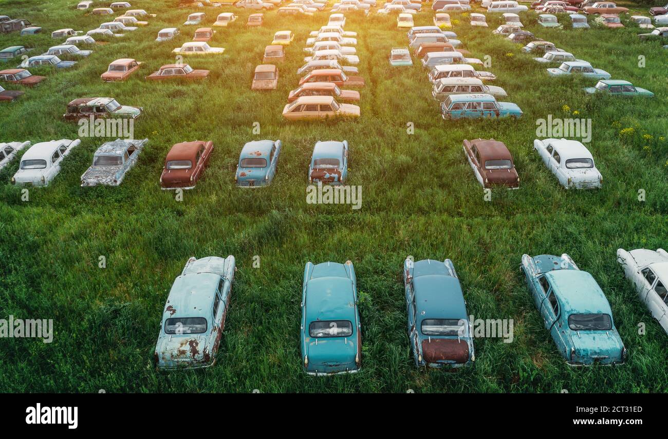 Vue aérienne des rangées de vieux véhicules rouillés abandonnés, des voitures rétro oubliées sur la prairie verte. Banque D'Images