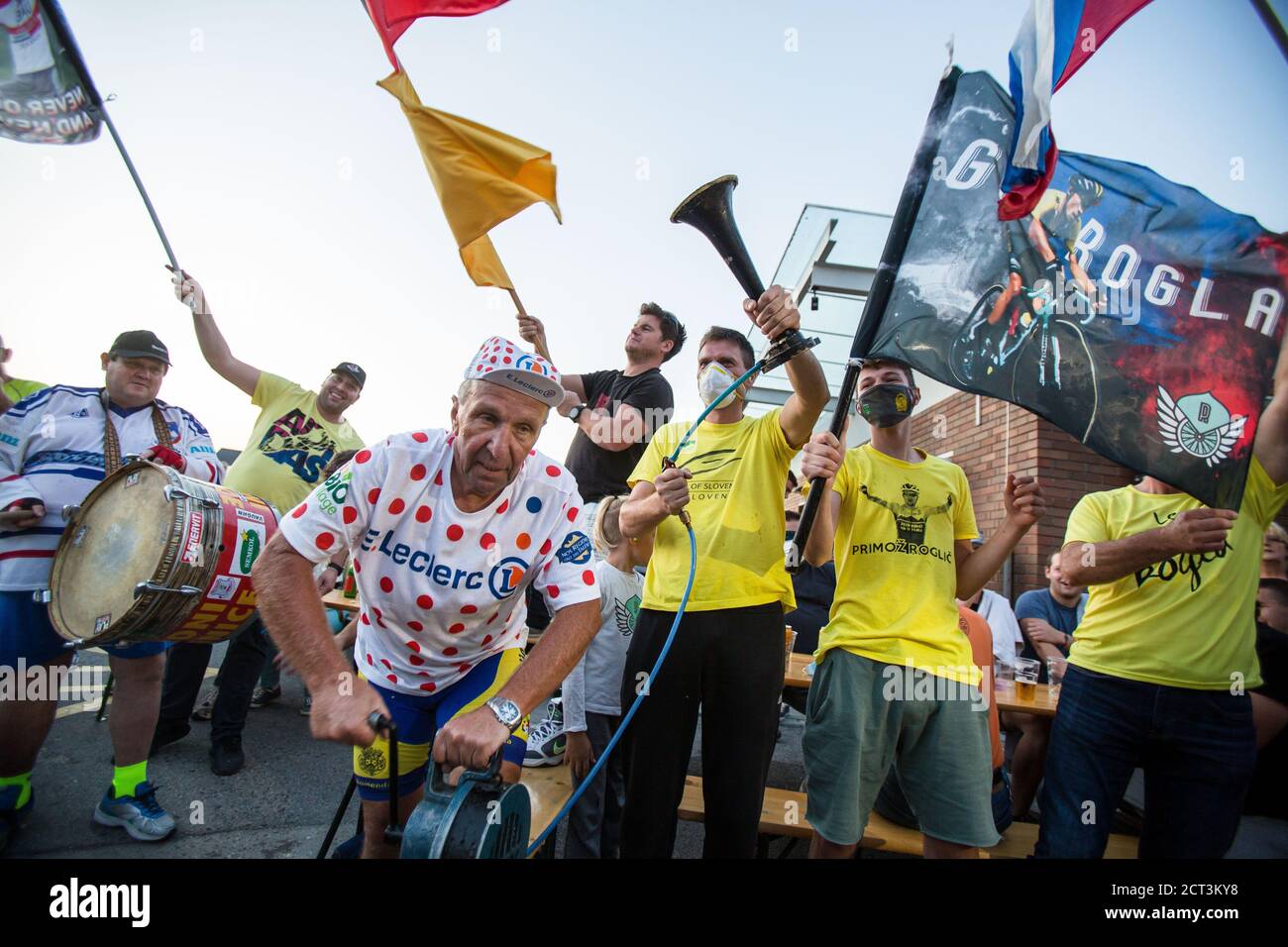 Un homme portant un t-shirt à pois lance une sirène tandis que les fans brandit des drapeaux en soutien aux cyclistes slovènes Tadej Pogacar et Primoz Roglic pendant la célébration.alors que Tadej Pogacar de Slovénie a gagné le Tour de France de cette année, les gens se sont rassemblés à Komenda, sa ville natale, pour célébrer et regarder la cérémonie de remise des prix à la télévision. Banque D'Images