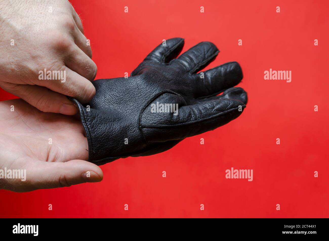 L'homme met des gants en cuir noir sur sa main. Homme adulte, caucasien, d'âge moyen. Vue latérale. Mise au point sélective. Banque D'Images